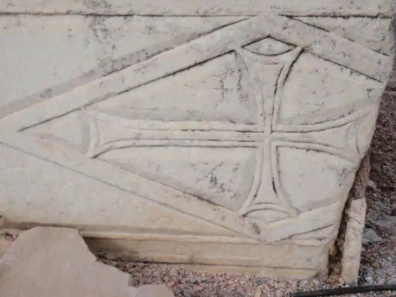 Asymmetrical cross inside a diamond engraved on a marble stone. Perhaps used as tombstone.